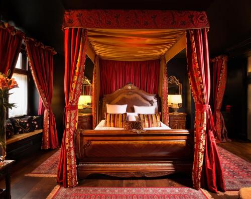 a bedroom with a canopy bed with red curtains at Kanonicza 22 in Krakow