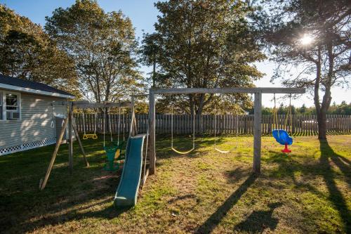 a playground with swings in a yard at Cavendish Lodge & Cottages in Cavendish