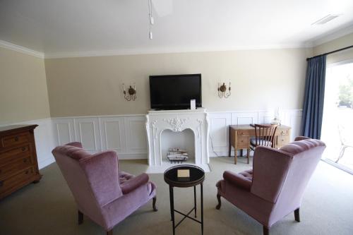 a living room with two chairs and a tv and a fireplace at The Rigdon House in Cambria