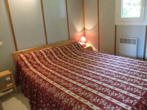 a bedroom with a bed with a red blanket at Chalet Des Menhirs in Moulin-Mage