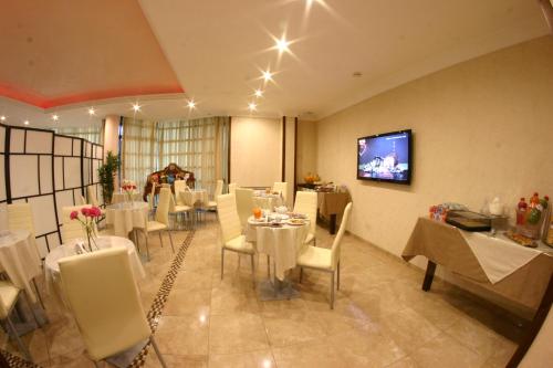 a dining room with white tables and chairs and a tv at Hotel Chic in SantʼAntimo