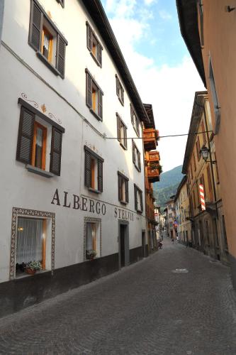 a street with a white building on a cobblestone road at Albergo Stelvio in Bormio