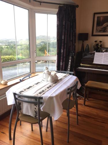 ein Esszimmer mit einem Tisch und einem Klavier in der Unterkunft Carrick House B&B in Killybegs