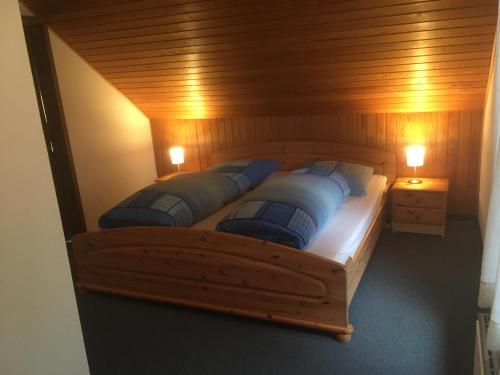 ブラウンラーゲにあるFerienwohnung Arnika inklusive Wäschepaketの木製ベッド(青い枕2つ付)