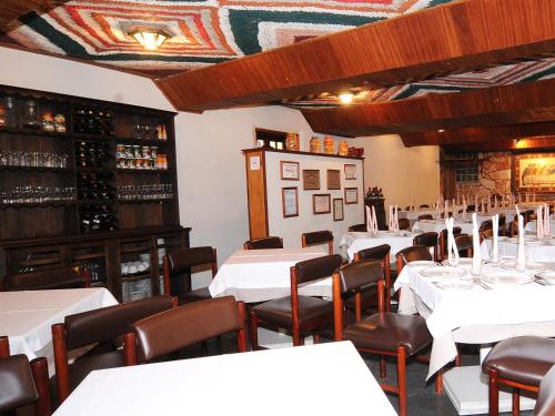 una sala da pranzo con tavoli e sedie bianchi di Pousada do Garimpo a Diamantina