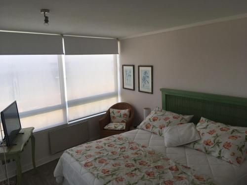 1 dormitorio con 1 cama, escritorio y ventanas en Departamento Punta Puyai, en Papudo