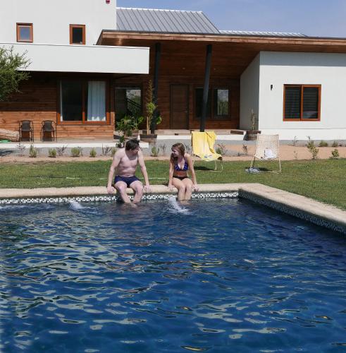 two people sitting on the edge of a swimming pool at Callihue Lodge in Santa Cruz