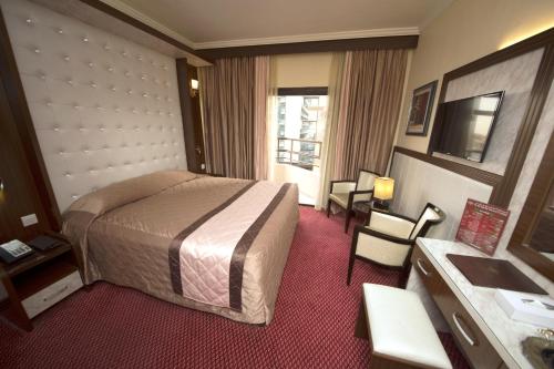 a hotel room with a bed and a table and chairs at Al Khaleej Grand Hotel in Dubai