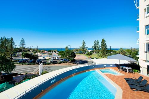 a large swimming pool with a balcony overlooking the ocean at ULTIQA Shearwater Resort in Caloundra