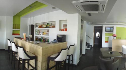 - un bar dans un restaurant avec des murs et des chaises blancs dans l'établissement Hotel Ifigenia, à Leptokaryá