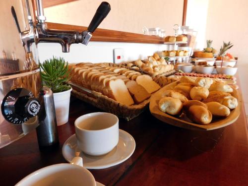 a table with a tray of bread and cups of coffee at Pousada dos Coqueiros Búzios in Búzios