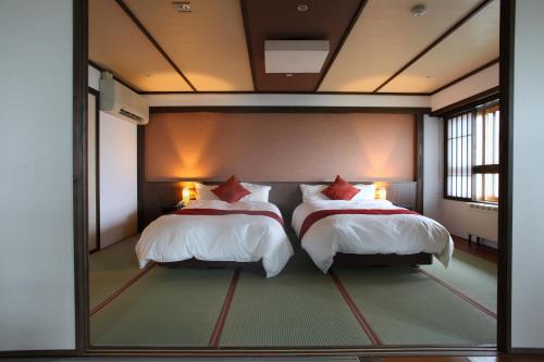 two beds in a room with a large mirror at Hotel Higashidate in Yamanouchi