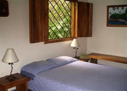 a bedroom with a blue bed and a window at Piscina Natural on the Sea in Cahuita