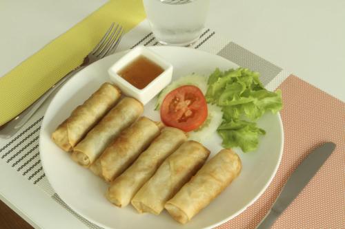 a plate of food with rolls and a tomato and lettuce at U Tiny Boutique Hotel Suvarnabhumi Bangkok - SHA Plus in Lat Krabang