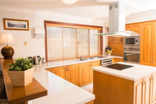 a kitchen with wooden cabinets and a white counter top at Ainslie Manor Guest House in Redcliffe