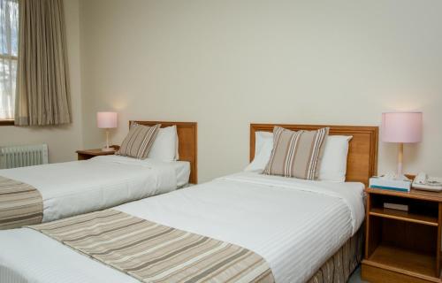 two beds in a hotel room with two lamps at La Maison Boutique Hotel in Katoomba