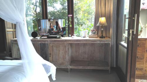 a bedroom with a dresser with a mirror and a bed at Griya Sriwedari in Ubud