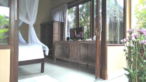 a room with a bed and a mirror and a window at Griya Sriwedari in Ubud