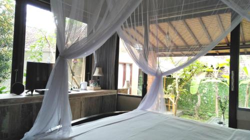 a bedroom with a bed with a canopy and a window at Griya Sriwedari in Ubud