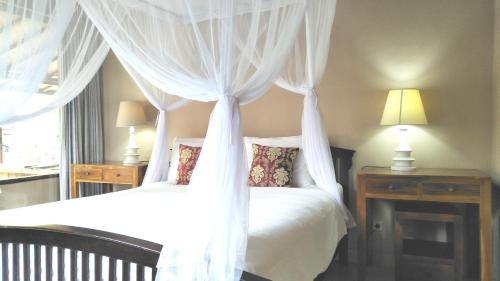 a bedroom with two beds with white curtains at Griya Sriwedari in Ubud