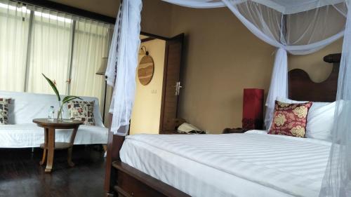 a bedroom with a canopy bed and a table and chair at Griya Sriwedari in Ubud