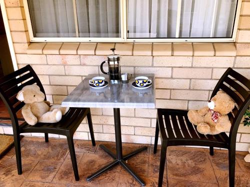 two teddy bears sitting on chairs next to a table at Starlight Motor Inn in Roma