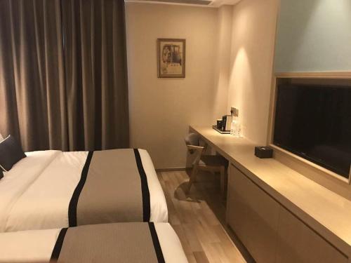 a hotel room with a bed and a flat screen tv at SHANGHAI-DECO Hotel-Free shuttle bus to Pudong Airport and Disneyland in Shanghai