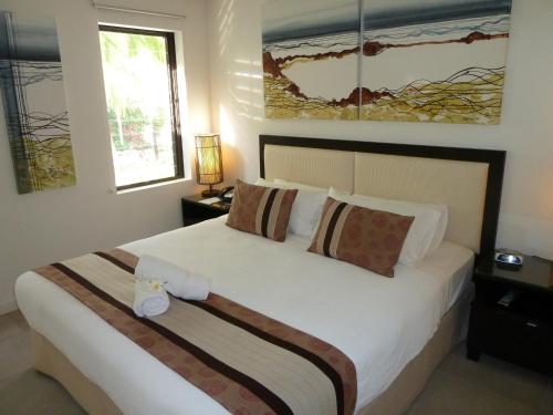 a bedroom with a large white bed with two windows at Penthouse 239 at See Temple Port Douglas in Port Douglas