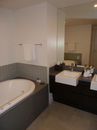 a bathroom with a tub and a sink and a mirror at Penthouse 239 at See Temple Port Douglas in Port Douglas