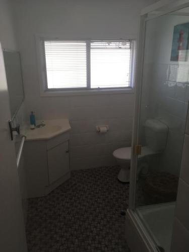 a bathroom with a sink and a toilet and a window at Tomaree Lodge in Nelson Bay