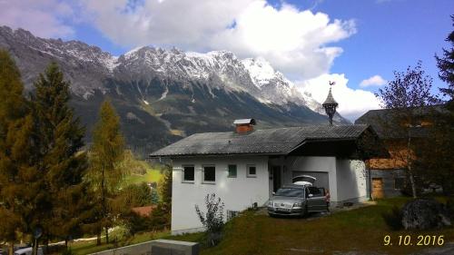 a car parked in front of a white house with a mountain at Rekreacni dum Grimming in Sankt Martin am Grimming