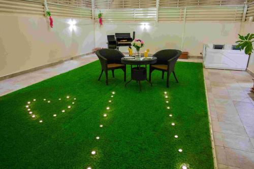 a room with a table and chairs on a green carpet at Rest Night Serviced Apartments- AlHamra in Riyadh