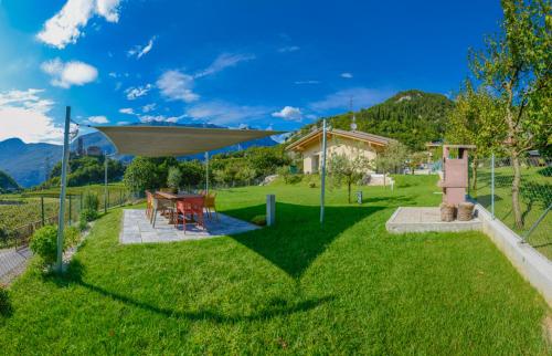 a backyard with a table and a umbrella at La Gazza Ladra Apartments - Garda Chill Out in Drena