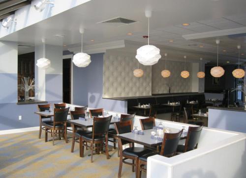 a dining room with tables and chairs and pendant lights at Causeway Bay Hotel in Lansing