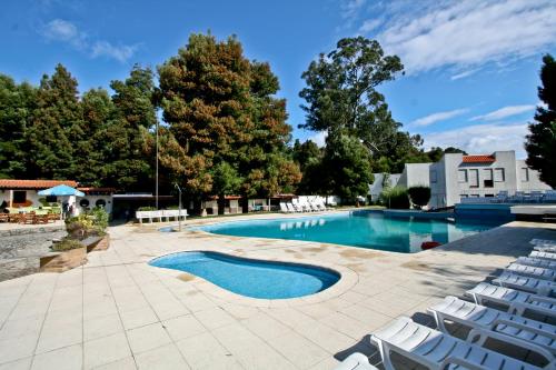 una piscina con sillas blancas en un patio en Nature & Beach Resort Aldeamento Turístico do Camarido, en Caminha