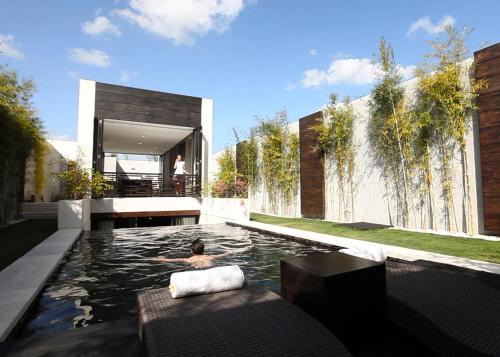 a person swimming in a pool in a house at eqUILIBRIA Seminyak - CHSE Certified in Seminyak