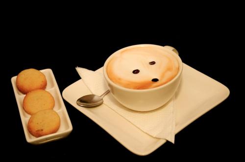 een kopje koffie met een getekend gezichtje naast een bord bij GemSuites Serviced Apartments State House in Nairobi