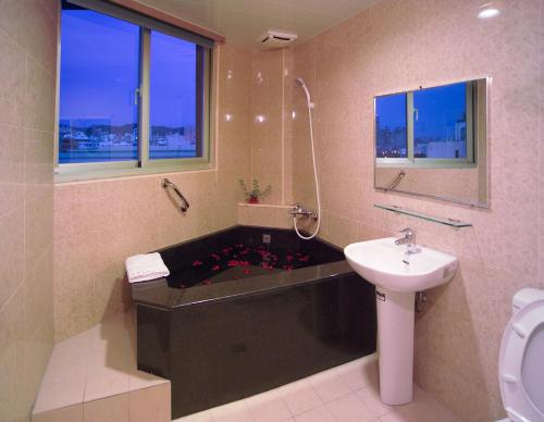 a bathroom with a bath tub with a sink and a toilet at Hua Tai Hotel in Hsinchu City