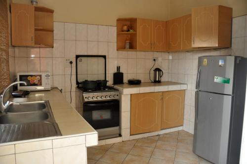 La cuisine est équipée d'un réfrigérateur en acier inoxydable et d'un évier. dans l'établissement Namugongo Holiday Home, à Kasiyirize