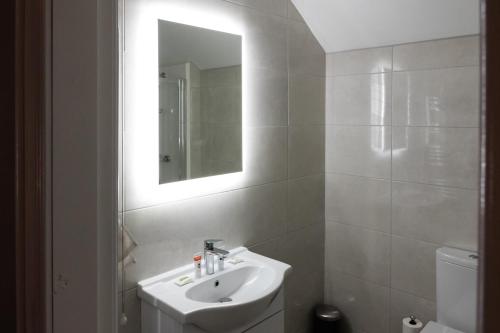 bagno bianco con lavandino e specchio di The Tailor's House Guest Rooms a Dunmoyle