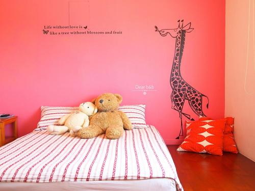 two teddy bears sitting on a bed in a bedroom at Ecotourism skim month B & B in Xiaoliuqiu