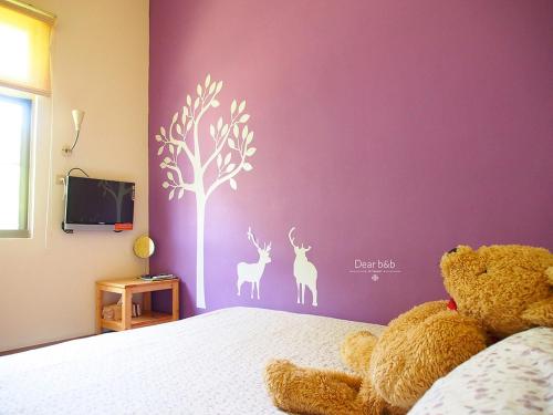 a teddy bear sitting on a bed in a bedroom at Ecotourism skim month B & B in Xiaoliuqiu