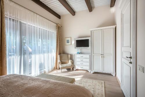 a bedroom with a bed and a tv and a window at Hotel Pušų paunksnėje in Palanga