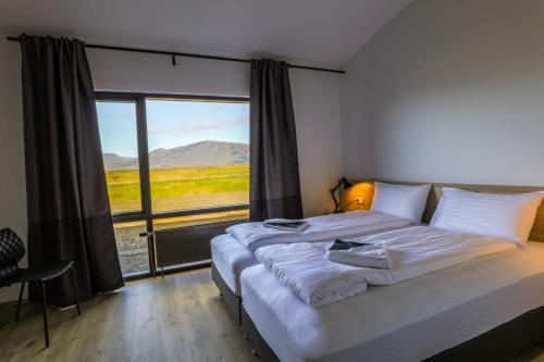 a bedroom with a large bed with a large window at Lilja Guesthouse in Höfn