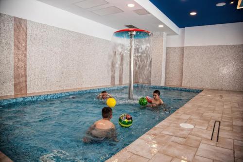 three boys playing in a swimming pool with a fountain at Hotel & Spa Tino Sveti Stefan in Ohrid