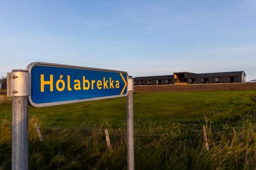 a blue street sign in front of a field at Lilja Guesthouse in Höfn