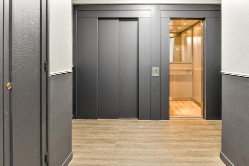 リールにあるWelkeys Apartment - Allee de Liegeの黒いドアと木製の床の廊下