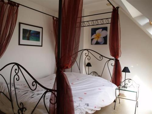a bedroom with a canopy bed with red curtains at Parc an Porz in Lannion
