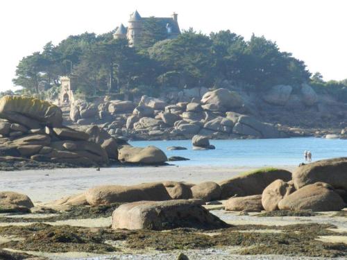 a beach with rocks and a house in the background at Parc an Porz in Lannion