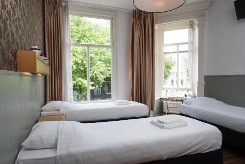 a hotel room with three beds and a window at Hotel Amsterdam Inn in Amsterdam